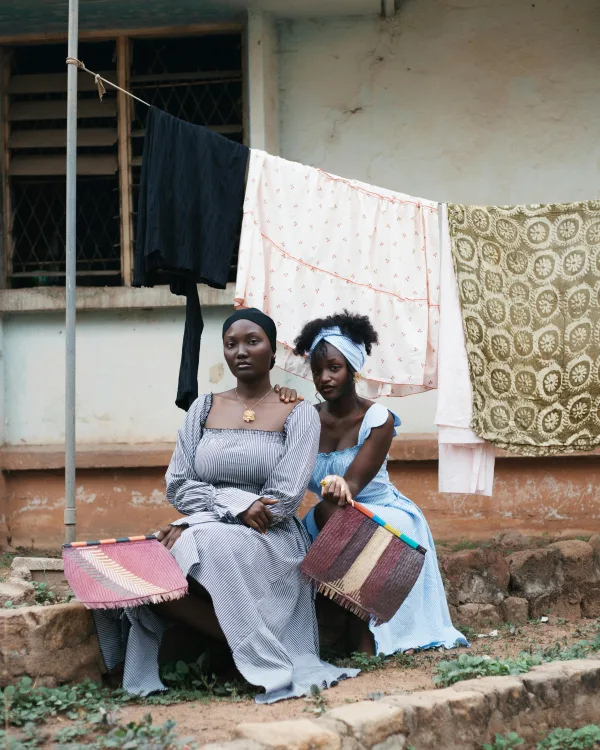 Portrait de deux femmes africaines en tenue traditionnelle devant une maison