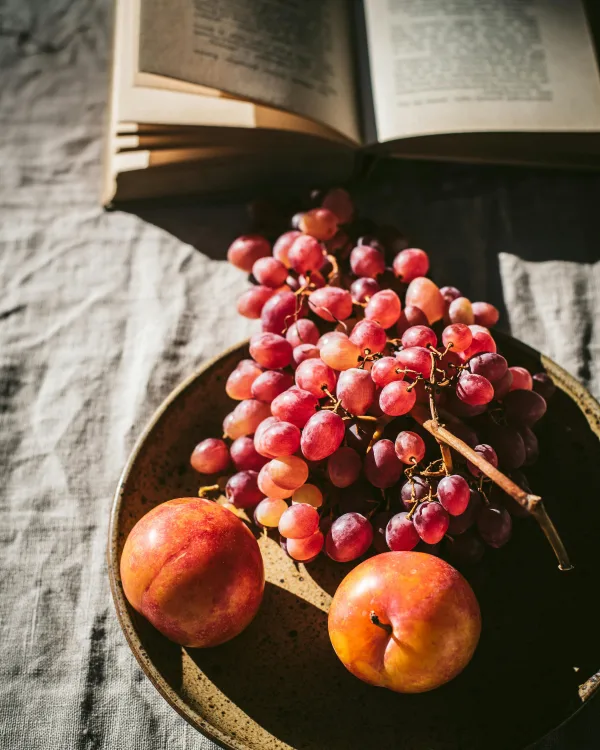 Nature morte élégante avec raisins, nectarines et livre ouvert