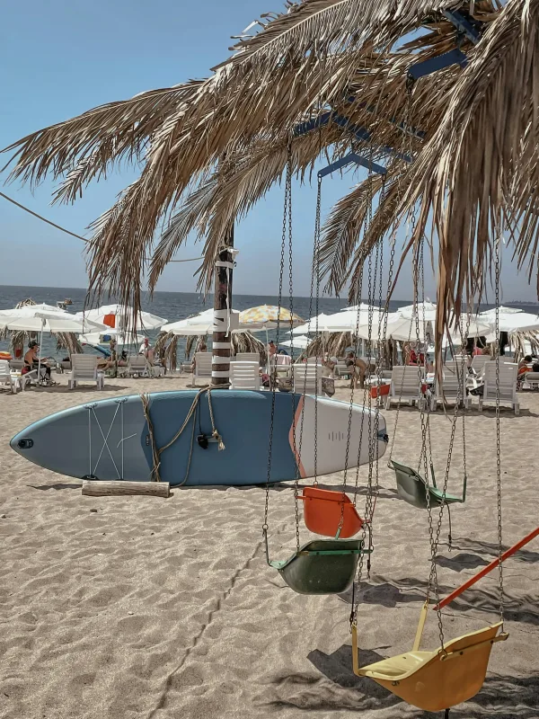 Plage tropicale avec palmiers, balançoires et planche de surf