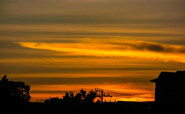 Coucher de soleil orange avec silhouettes urbaines et ciel dramatique