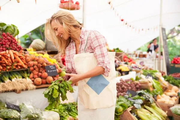 Femme achetant des légumes frais dans un marché bio