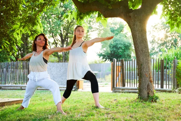 Cours de yoga en plein air sous un arbre dans un jardin