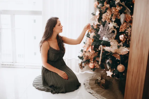 Femme décorant un sapin de Noël dans un intérieur chaleureux