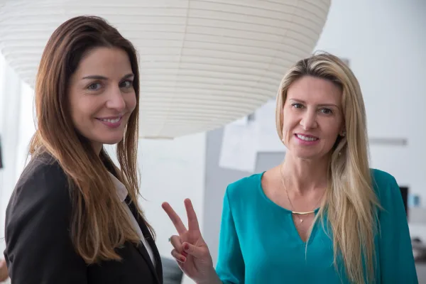Deux femmes d’affaires souriantes dans un environnement professionnel moderne