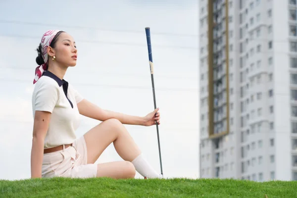 Golfeuse assise sur un parcours de golf avec un club à la main