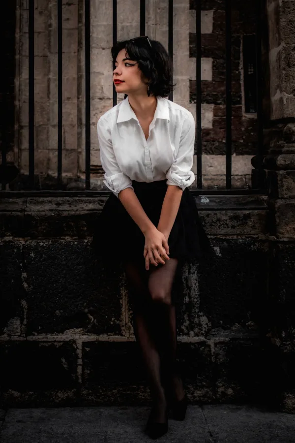 Jeune femme élégante assise devant une architecture historique dans un style urbain chic