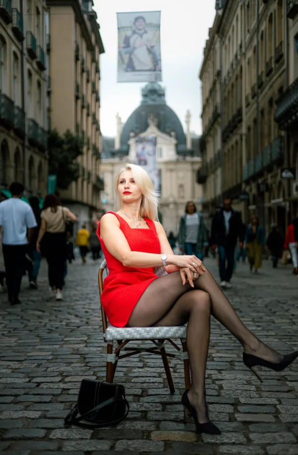 Femme élégante en robe rouge assise dans une rue historique animée