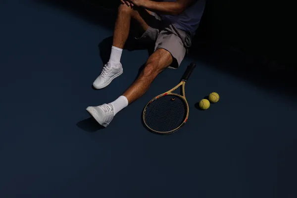 Raquette et balles de tennis sur un court avec joueur au repos
