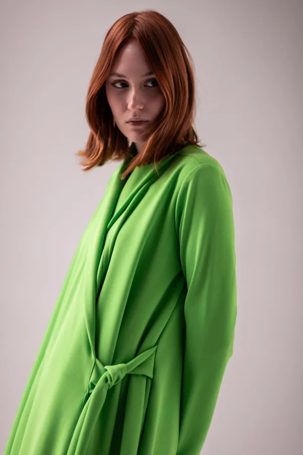Portrait de femme rousse en manteau vert élégant sur fond neutre