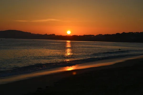 Coucher de soleil sur une plage avec reflets dorés sur la mer