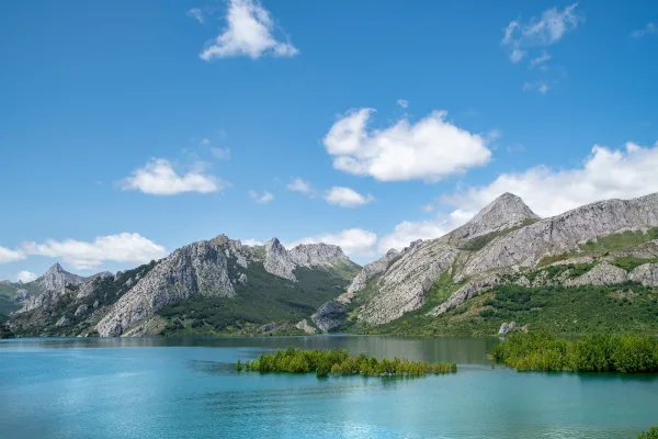 Lac de montagne entouré de sommets rocheux sous un ciel bleu
