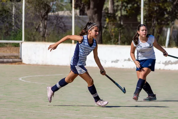 Jeunes joueuses de hockey sur gazon en plein match sur terrain extérieur