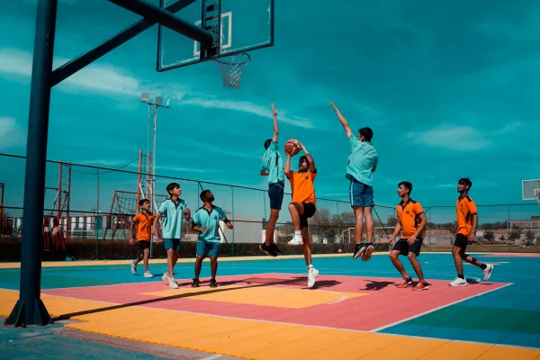 Jeunes joueurs disputant un match de basketball sur un terrain extérieur
