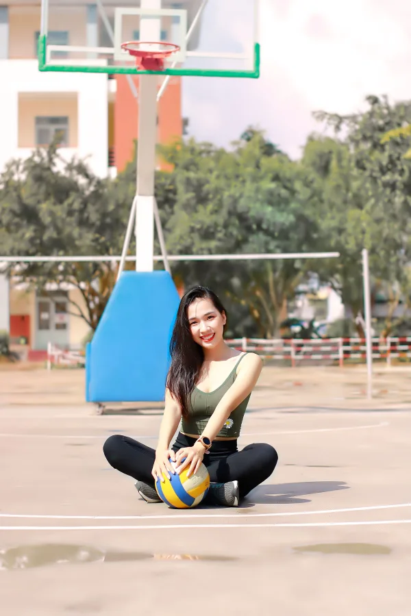 Jeune sportive assise sur un terrain de basketball avec un ballon de volley-ball
