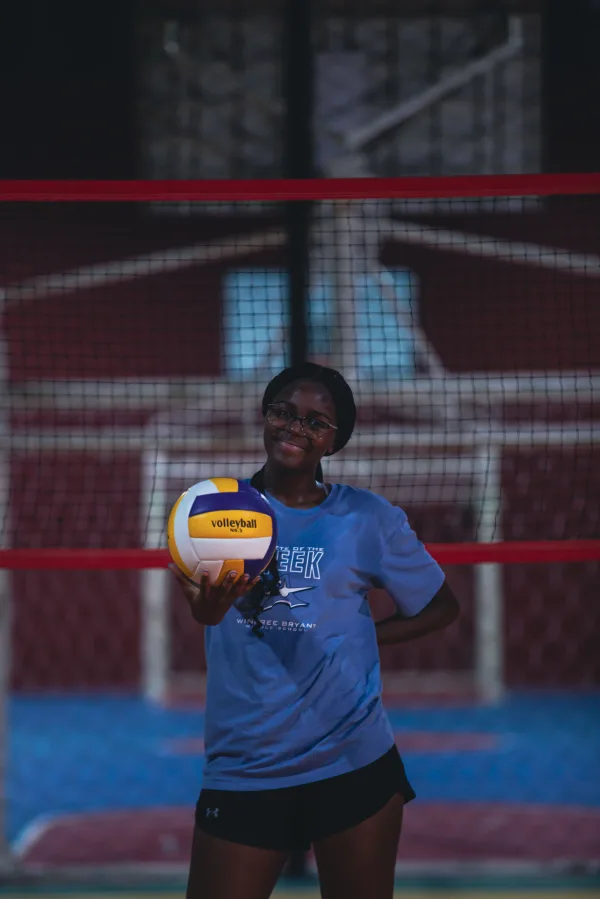 Joueuse de volleyball posant avec un ballon sur un terrain intérieur
