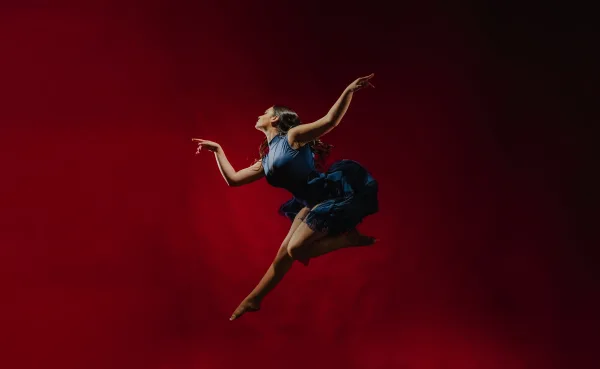Danseuse contemporaine en plein saut sur fond rouge – photographie artistique