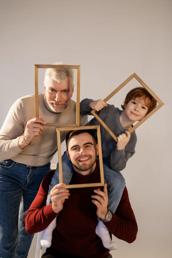 Portrait intergénérationnel d’un grand-père, d’un père et d’un enfant avec cadres photo