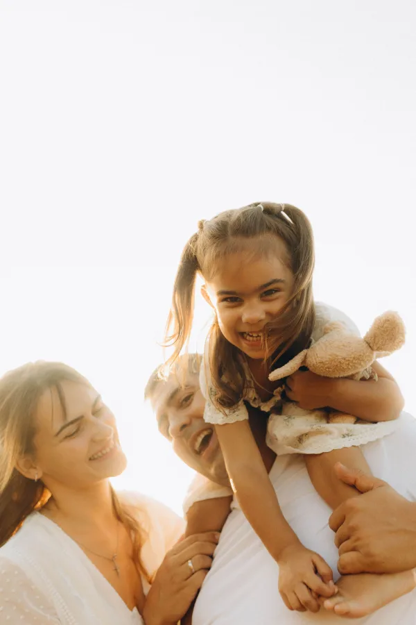 Petite fille souriante portée sur les épaules de son père en famille