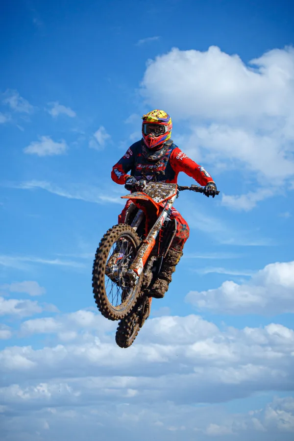 Pilote de motocross en plein saut sous un ciel bleu