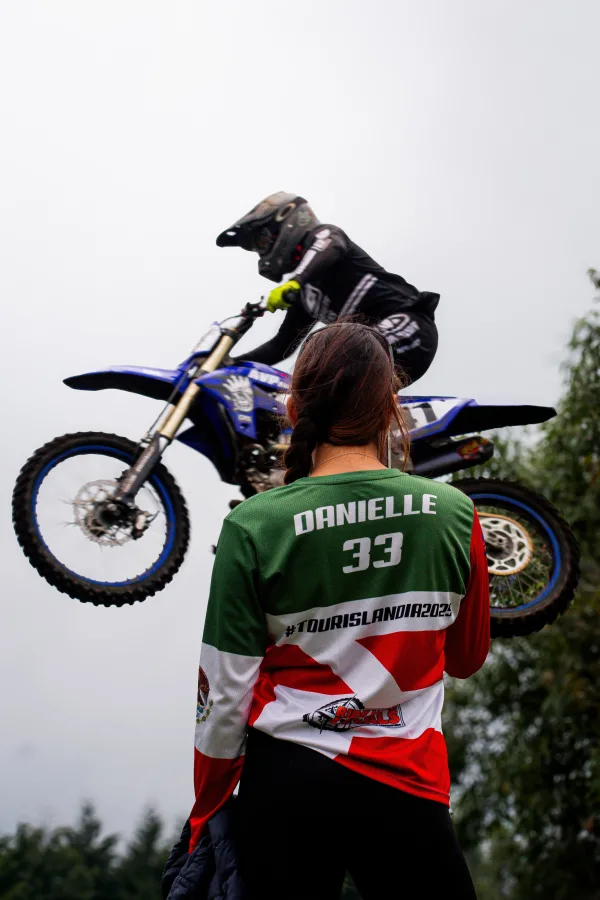 Spectatrice de motocross observant un pilote en plein saut aérien