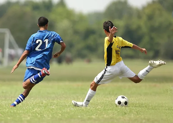 Deux joueurs de football en duel lors d’un match sur terrain en herbe