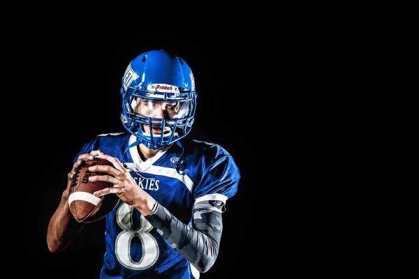 Quarterback de football américain prêt à lancer le ballon – Fond noir
