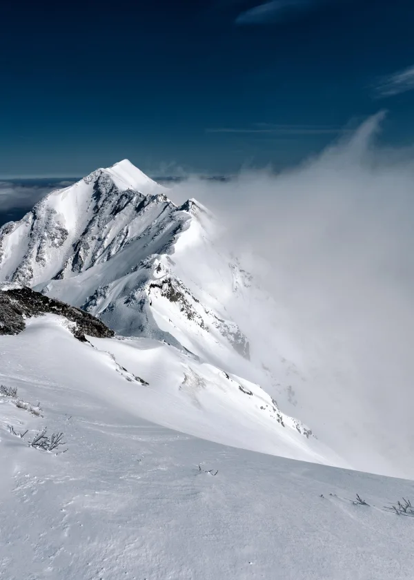 Sommet enneigé dominant une mer de nuages en haute montagne