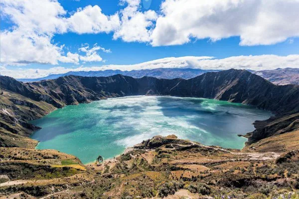 Lac de cratère volcanique aux eaux turquoise entouré de montagnes