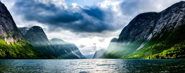 Fjord majestueux entre montagnes verdoyantes sous un ciel orageux