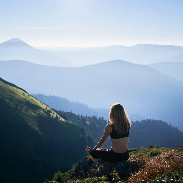Femme méditant face aux montagnes au lever du soleil