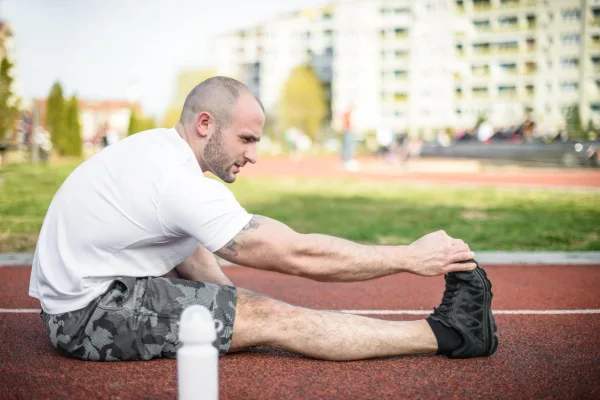 Sportif s'étirant sur une piste d'athlétisme après une séance d'entraînement