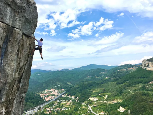 Grimpeur escaladant une falaise avec vue panoramique sur les montagnes