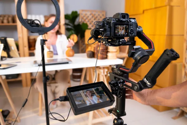 Créatrice de contenu filmant une vidéo avec une caméra professionnelle et un éclairage annulaire