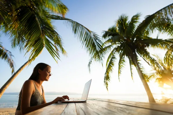 Nomade digitale travaillant sur une plage tropicale avec un ordinateur portable