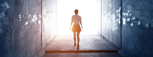 Personne marchant vers la lumière au bout d'un tunnel, symbole d'espoir et de transformation