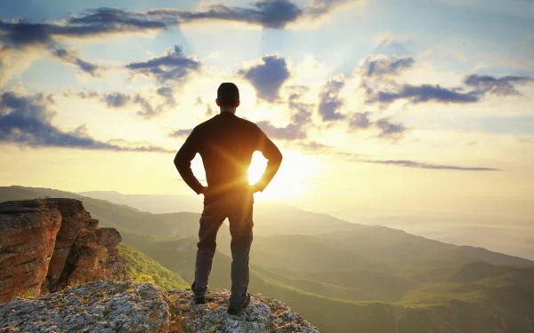 Homme debout au sommet d'une montagne, symbole de confiance en soi, de réussite et de dépassement de soi