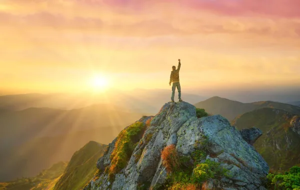 Personne au sommet d'une montagne levant le poing, symbole de confiance en soi, de victoire et de dépassement de soi