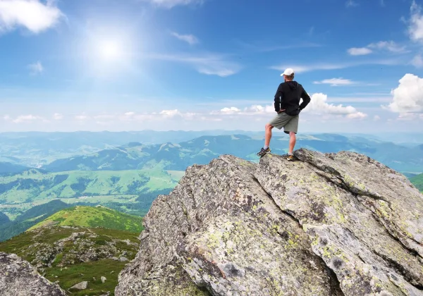 Randonneur au sommet d'une montagne contemplant l'horizon, symbole de confiance en soi et de réussite personnelle