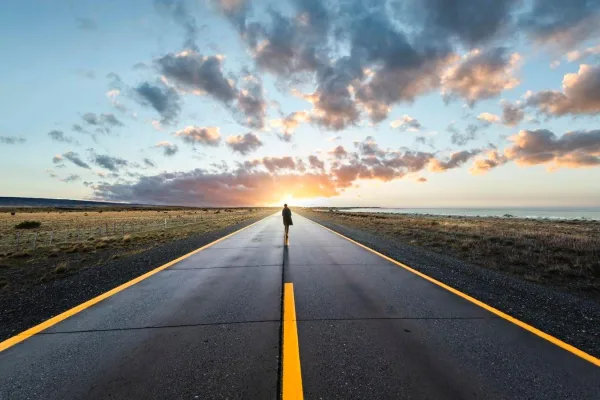 Personne marchant vers l'horizon sur une route infinie, symbole de persévérance, d'objectifs et de développement personnel