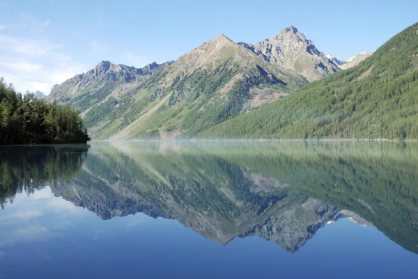 Lac de montagne aux eaux calmes reflétant une chaîne de sommets majestueux