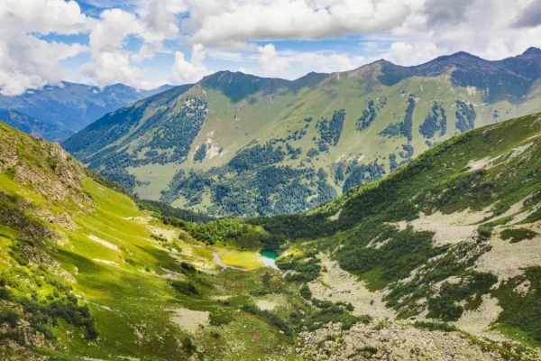 Vallée alpine verdoyante avec lac de montagne niché au cœur des sommets