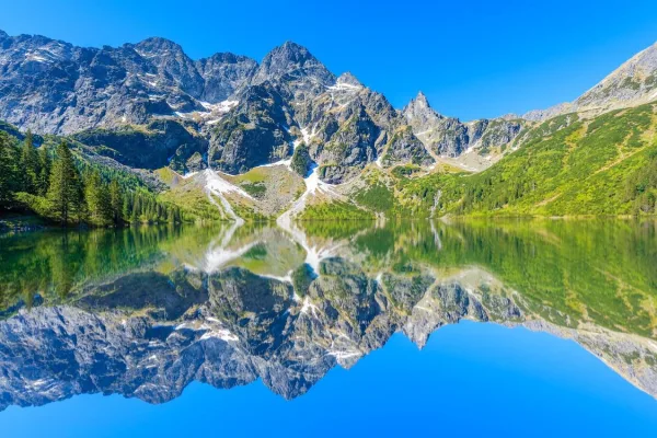 Lac de montagne aux eaux cristallines reflétant une majestueuse chaîne de sommets