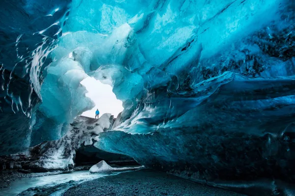 Explorateur dans une grotte de glace bleue au cœur d'un glacier