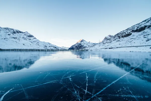 Lac gelé entouré de montagnes enneigées dans un paysage hivernal