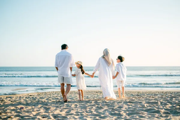Famille marchant main dans la main sur une plage au bord de l'océan