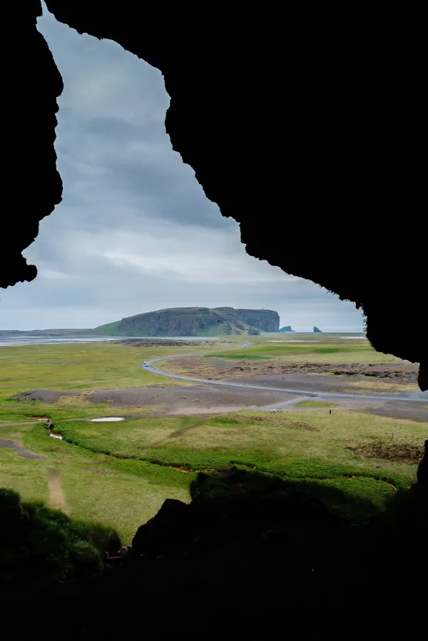Vue panoramique depuis une grotte sur un paysage côtier et une route sinueuse