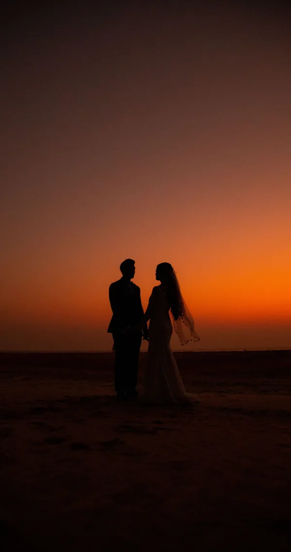 Silhouette de jeunes mariés au coucher du soleil sur une plage