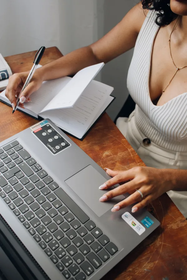 Femme entrepreneure prenant des notes sur ordinateur portable dans un espace de travail